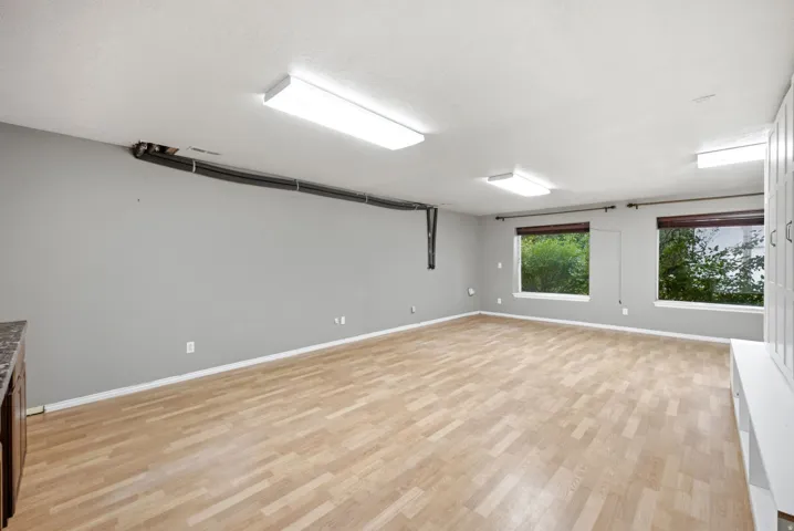 Main home basement. Spacious room featuring wood-finish flooring, multiple windows, and extensive built-in white cabinetry