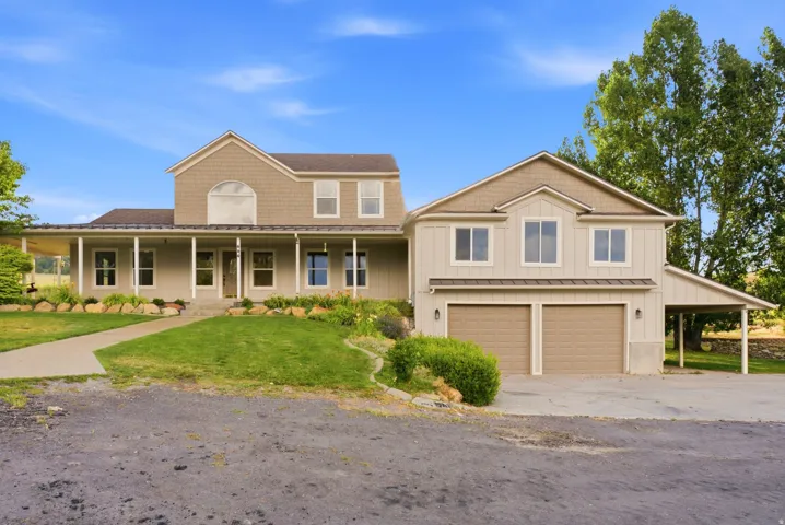 Two-story residence featuring a covered front porch, an attached two-car garage, and a carport