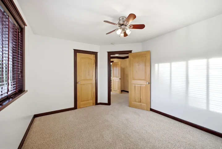 Upstairs bedroom. Spacious room featuring light-toned carpeting, white walls, and wood-finish trim