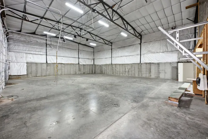 Expansive warehouse space featuring a concrete floor, concrete block walls, and insulated upper walls