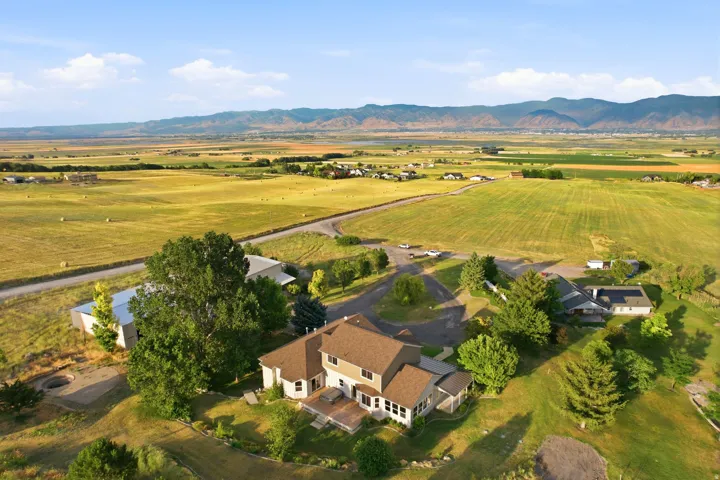 Expansive rural property featuring a two-story residence with a brown shingle roof and light-toned siding