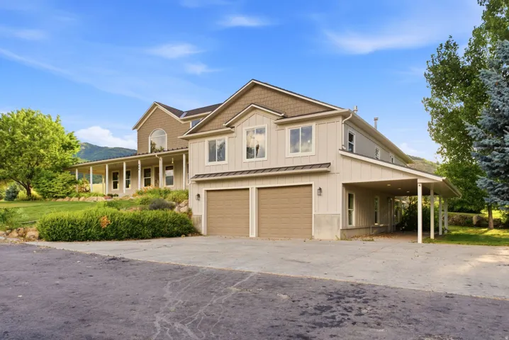 Multi-level residence featuring a two-car garage, an extended covered carport, and a covered front porch with supporting columns