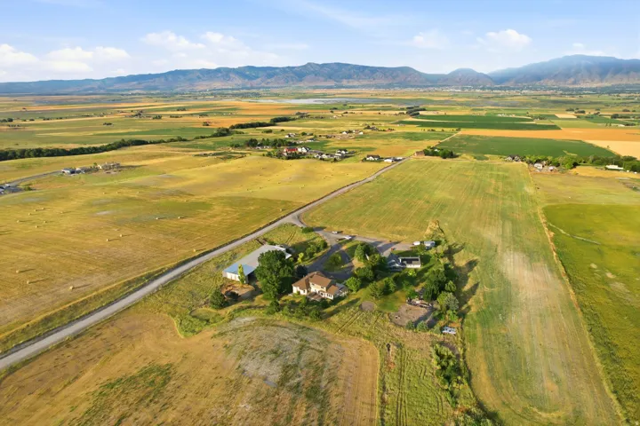 Expansive agricultural landscape featuring multiple fields, distant mountain ranges, and a rural road system