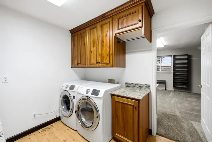 Main floor Dedicated laundry area featuring wood-finish flooring, white walls, and built-in upper cabinetry