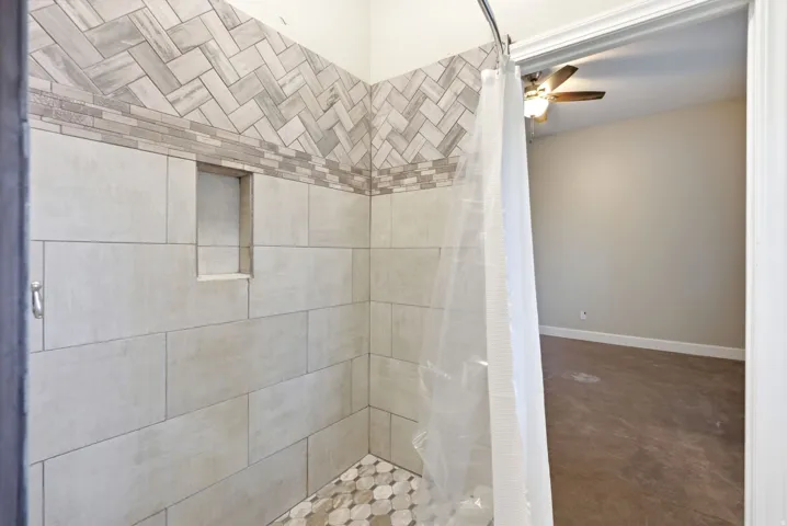 Tiled shower featuring a built-in niche, patterned mosaic floor, and herringbone accent tile