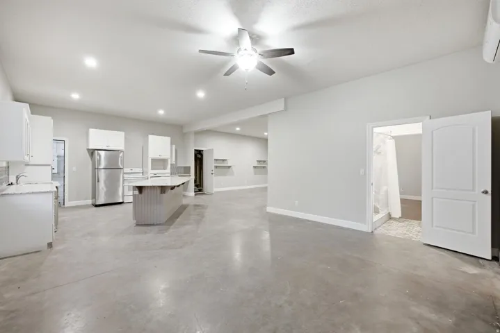 Open-concept living area featuring polished concrete flooring, recessed lighting, a ceiling fan, and light gray wall tones