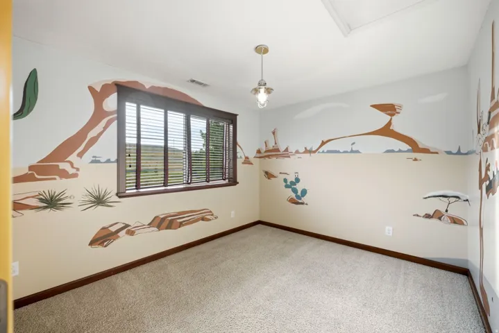 Upstairs bedroom. Carpeted room featuring a large window with horizontal blinds and dark wood trim