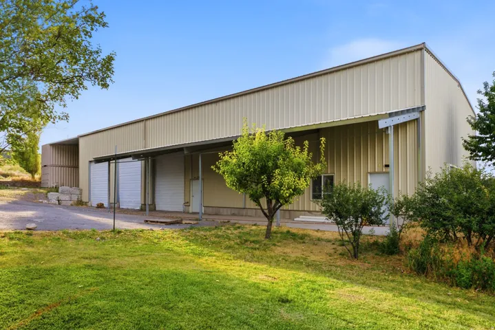 Long industrial building featuring corrugated metal siding, covered exterior loading areas, multiple roll-up doors, and a pedestrian entrance