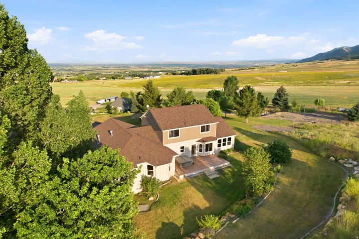 Expansive property featuring a multi-level residence with a large rear patio, mature trees, and a spacious green lawn