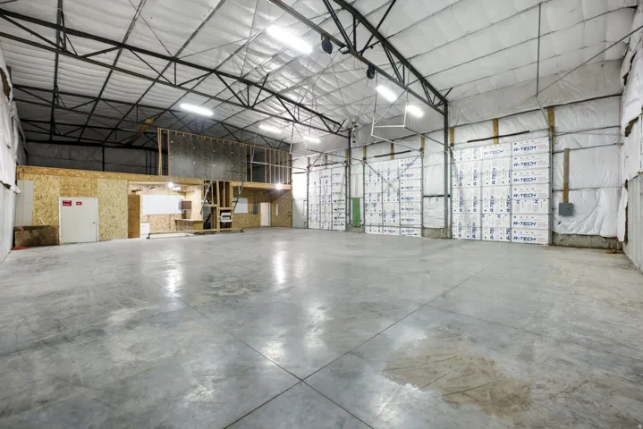 Expansive concrete flooring in a large open warehouse space with exposed metal truss ceiling