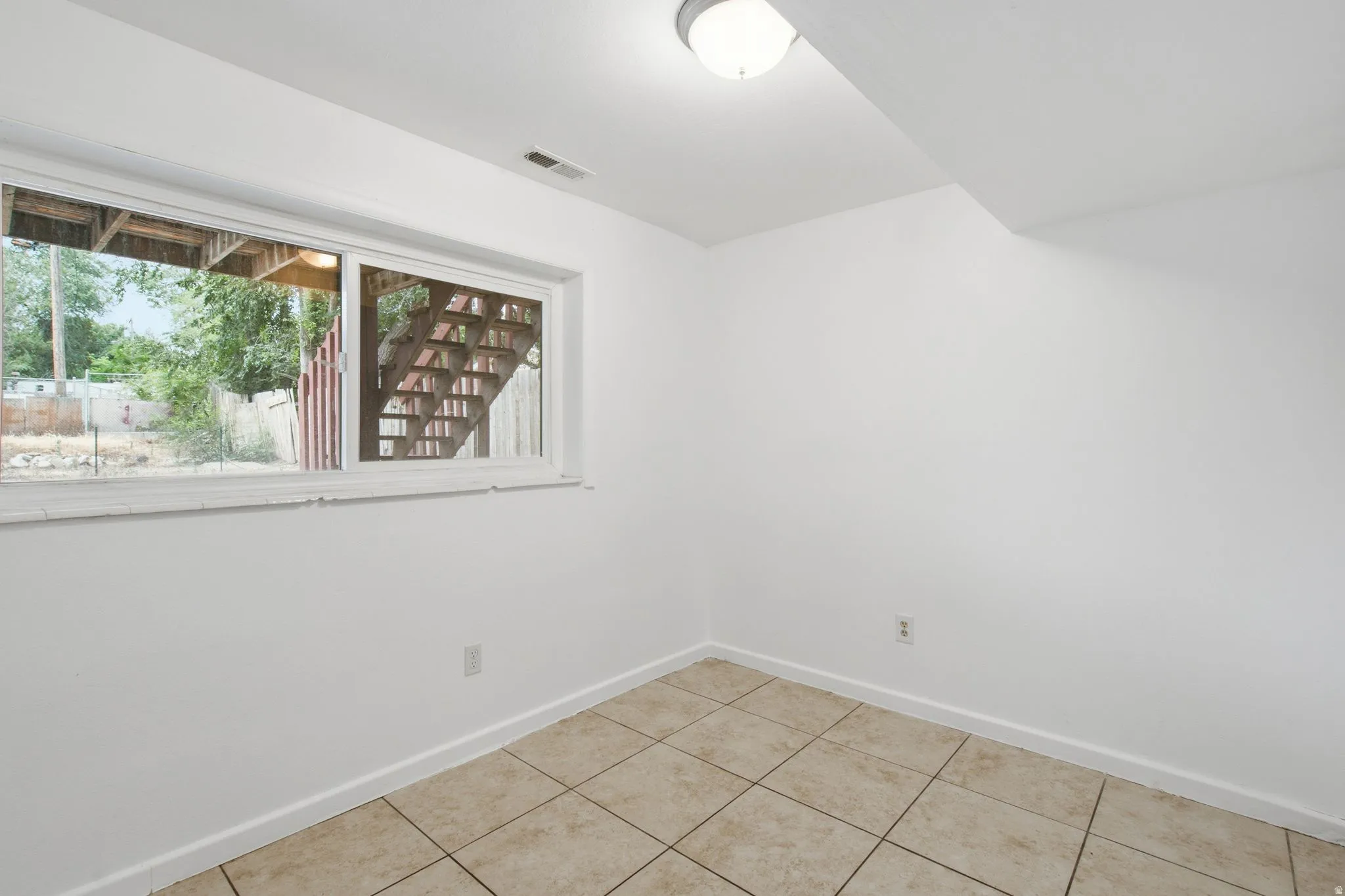 Windowed room featuring light-toned square floor tiles and white walls