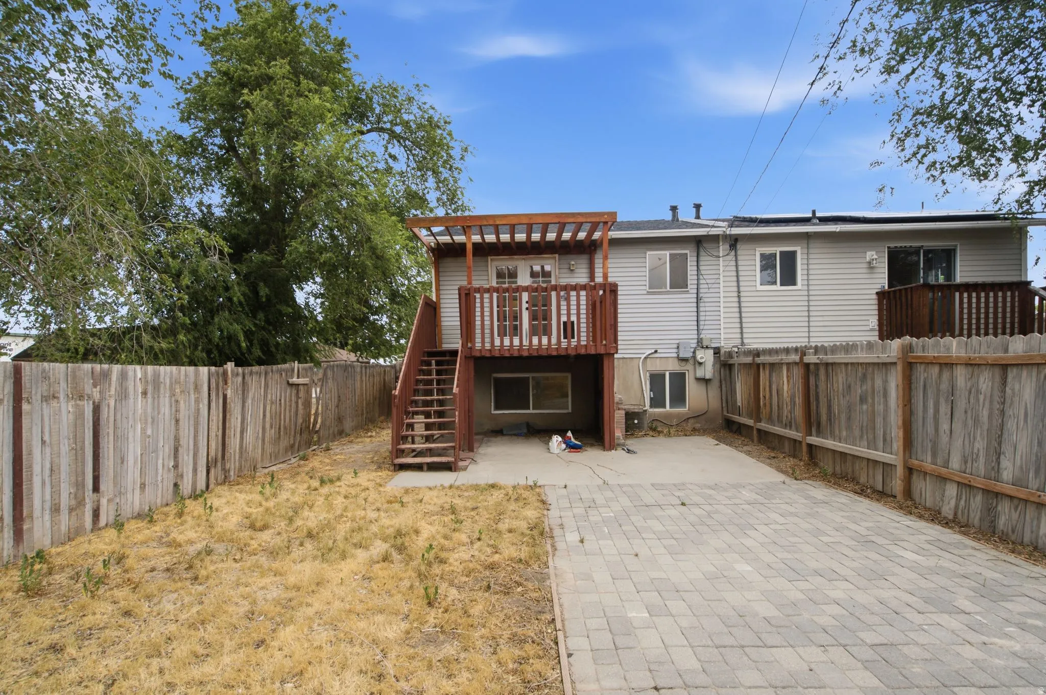 Rear exterior featuring two-story wood deck with pergola, wood privacy fencing, and a paver stone patio area