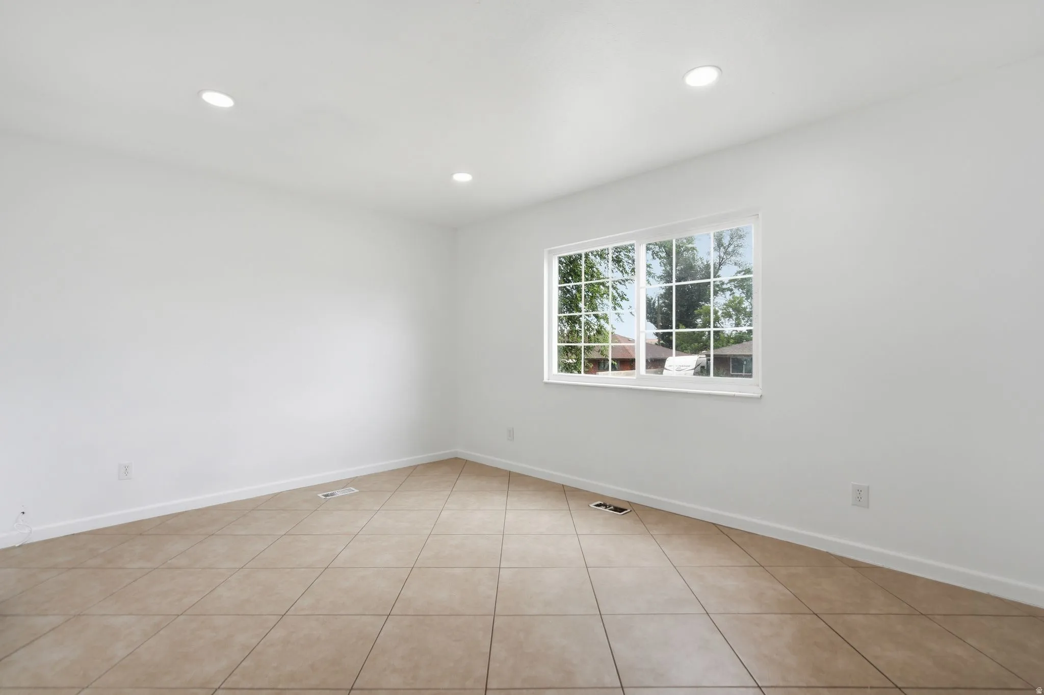 Room featuring a window with grid panes, recessed lighting, white walls, and beige tile flooring