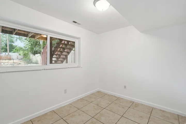 Windowed room featuring light-toned square floor tiles and white walls