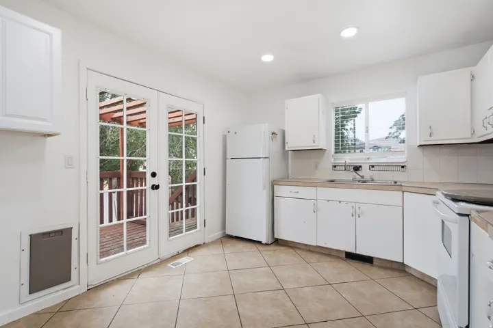Kitchen featuring white cabinetry, light-toned tile flooring, recessed lighting, and a window above the sink