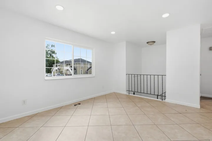 Spacious interior room featuring tile flooring, white walls, recessed ceiling lights, and a window providing natural light
