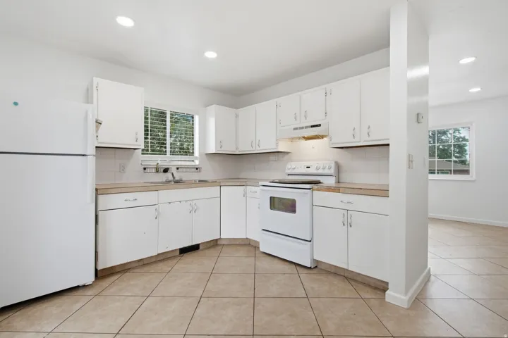 Bright kitchen featuring white cabinetry, a white refrigerator, a white electric range, recessed lighting, and tile flooring