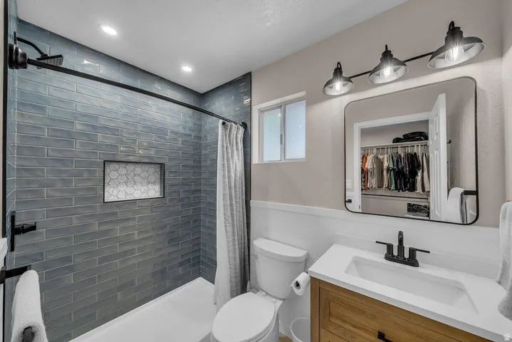 Shower with blue subway tile surround, recessed hexagonal tile niche, and matte black fixtures