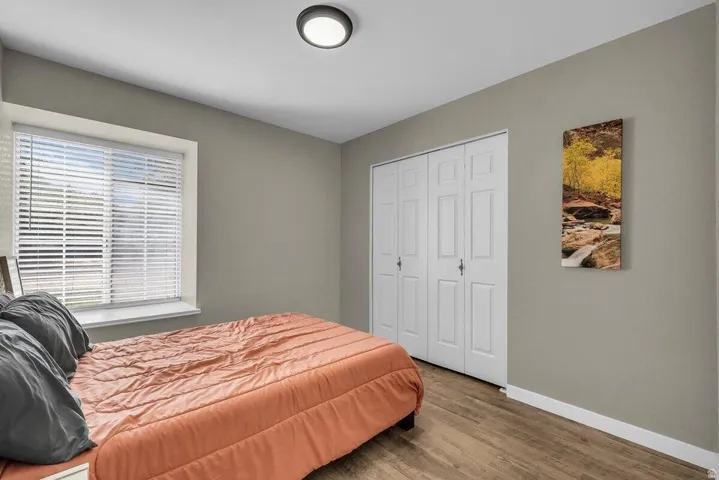 Neutral tone wall paint with a white trim, wood-finish flooring, and a window featuring horizontal blinds