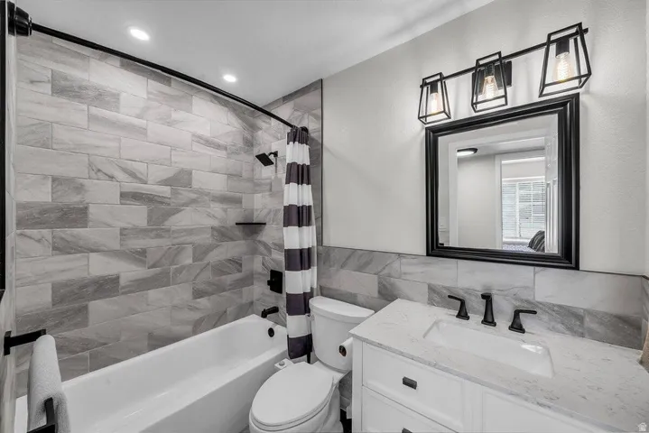 Bathroom featuring a white vanity with a rectangular undermount sink, matte black faucet, and a framed mirror