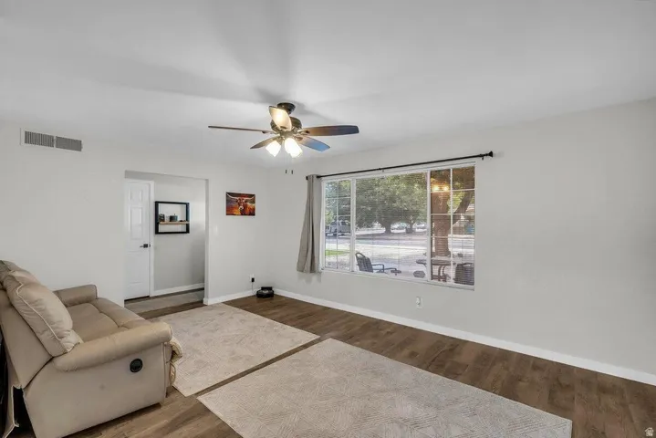 Bright living space featuring wood-finish flooring and a ceiling fan with integrated lighting