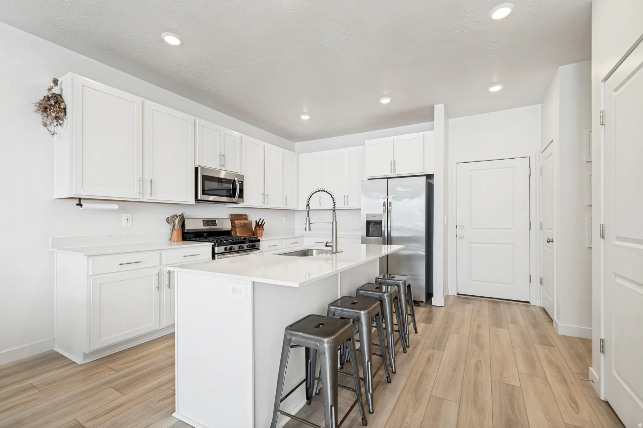Kitchen with light wood-finish flooring, white cabinetry, and recessed lighting