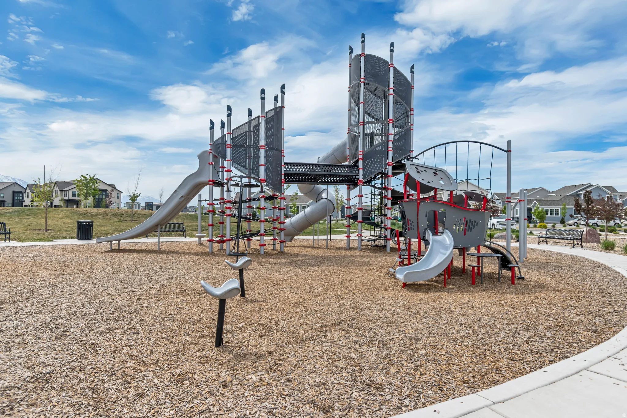 Community playground featuring multiple slides, climbing structures, and protective wood chip surfacing