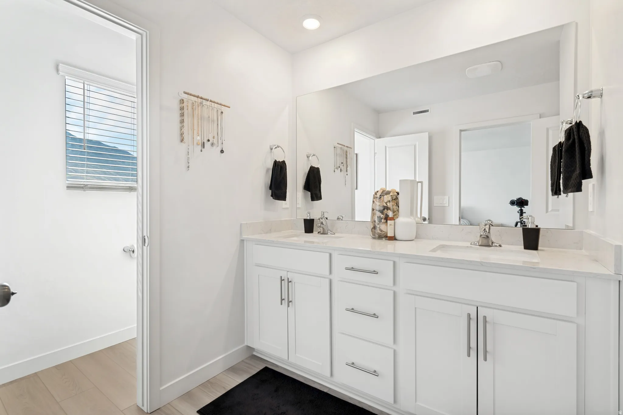 Dual sink vanity featuring white cabinetry and light-colored countertops