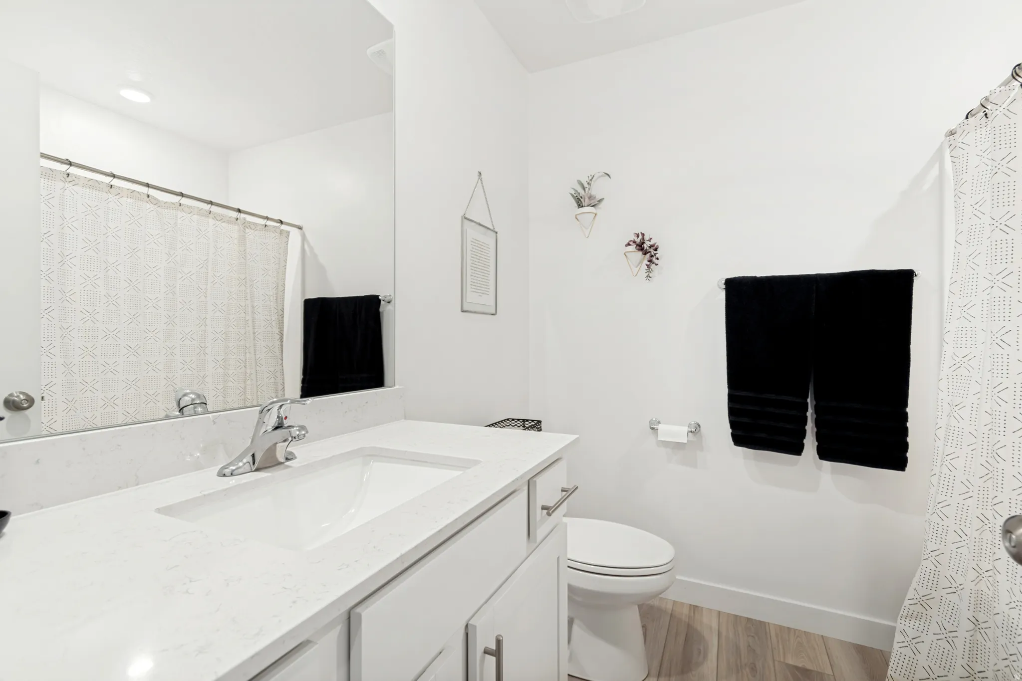 Bathroom featuring a white vanity with an integrated sink, chrome faucet, and a large mirror