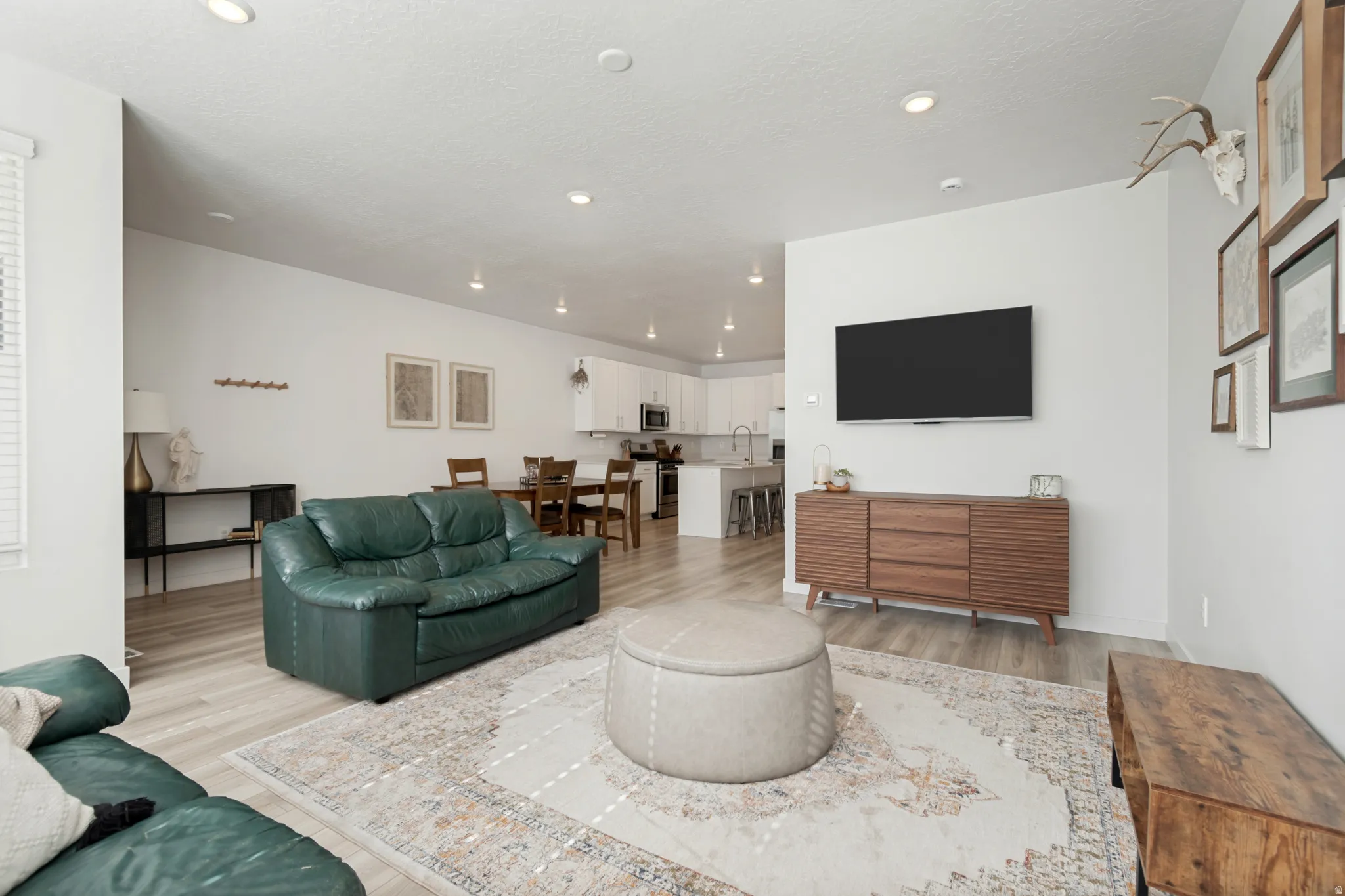 Open-concept living area with light wood-finish flooring, recessed lighting, and a neutral color palette
