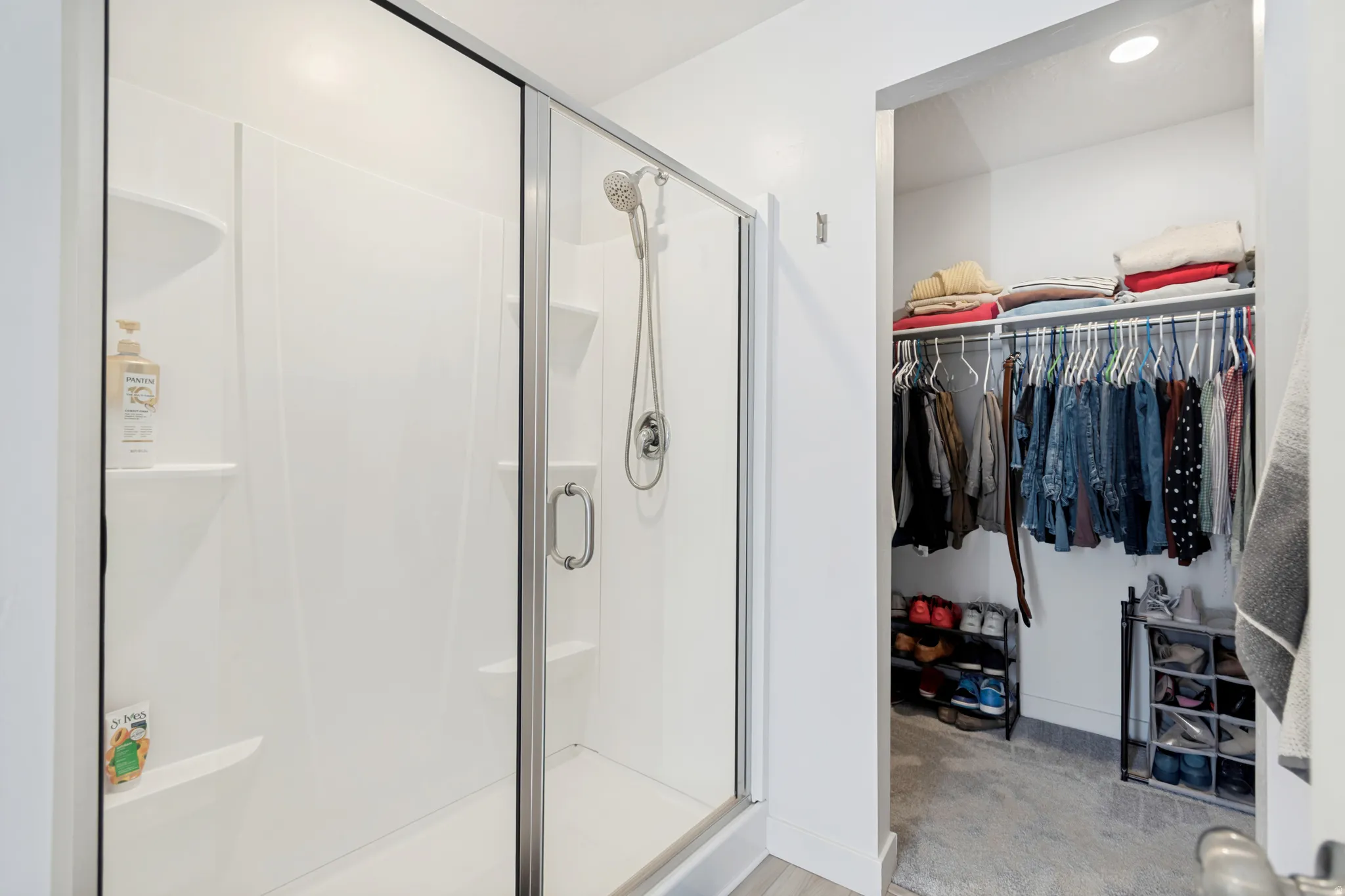 Shower enclosure with a clear glass door, white shower surround, and integrated shelving