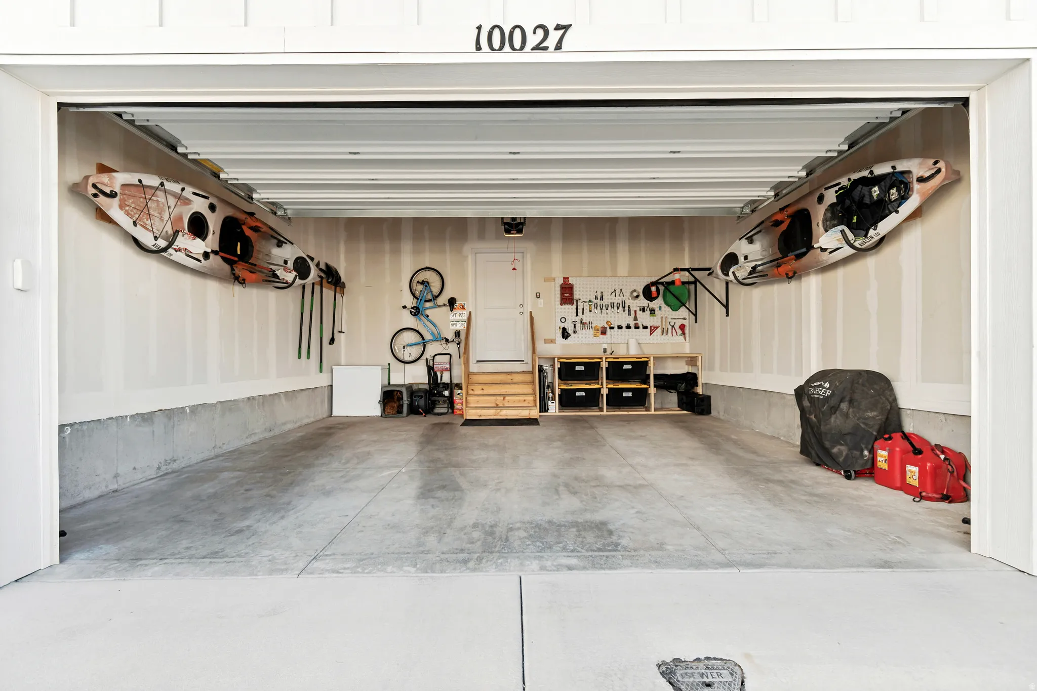 Spacious garage with concrete flooring, unfinished walls, and a built-in workbench with storage