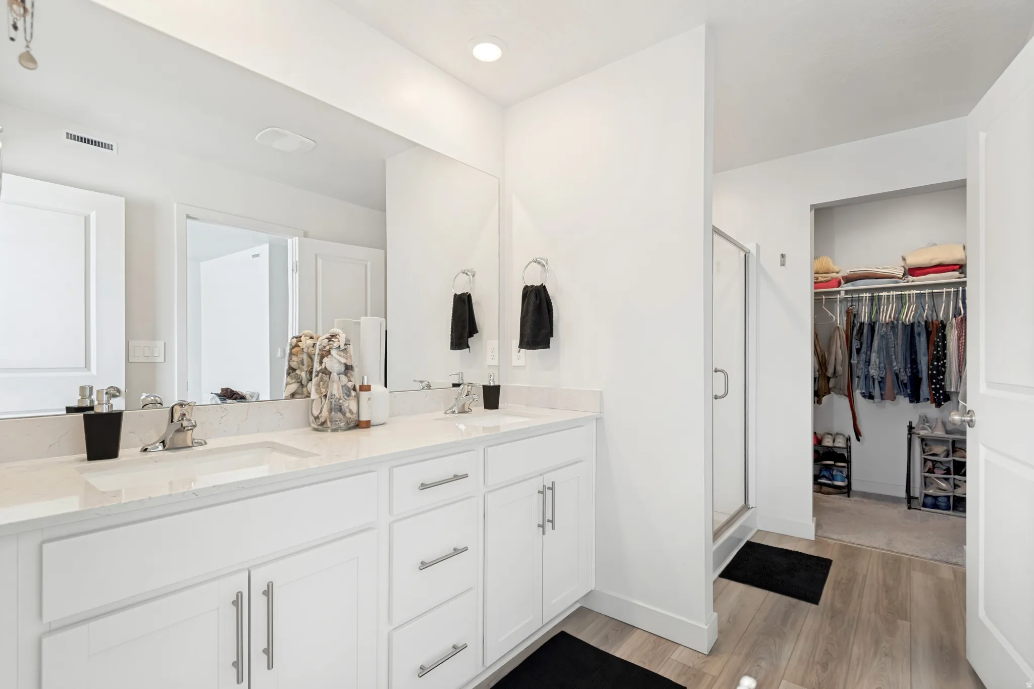 Bathroom featuring a dual vanity with white cabinetry, light-toned countertops, and chrome fixtures