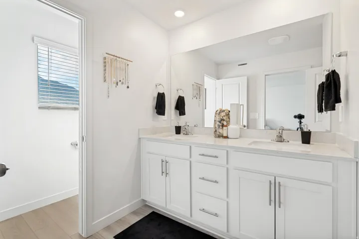 Dual sink vanity featuring white cabinetry and light-colored countertops