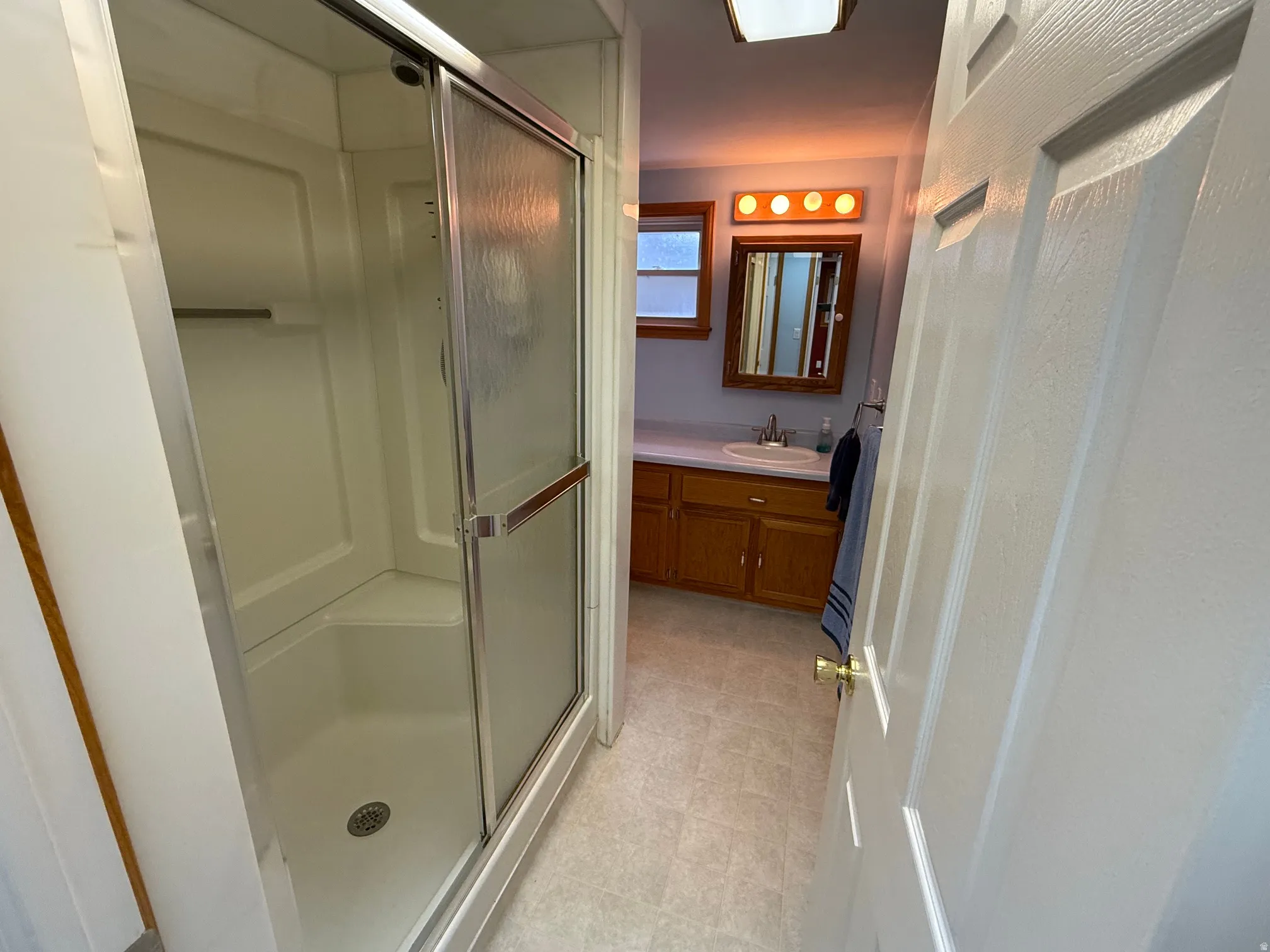 3/4 Bathroom featuring a standing shower with sliding glass doors and a single vanity with a white countertop and wood-finish cabinetry