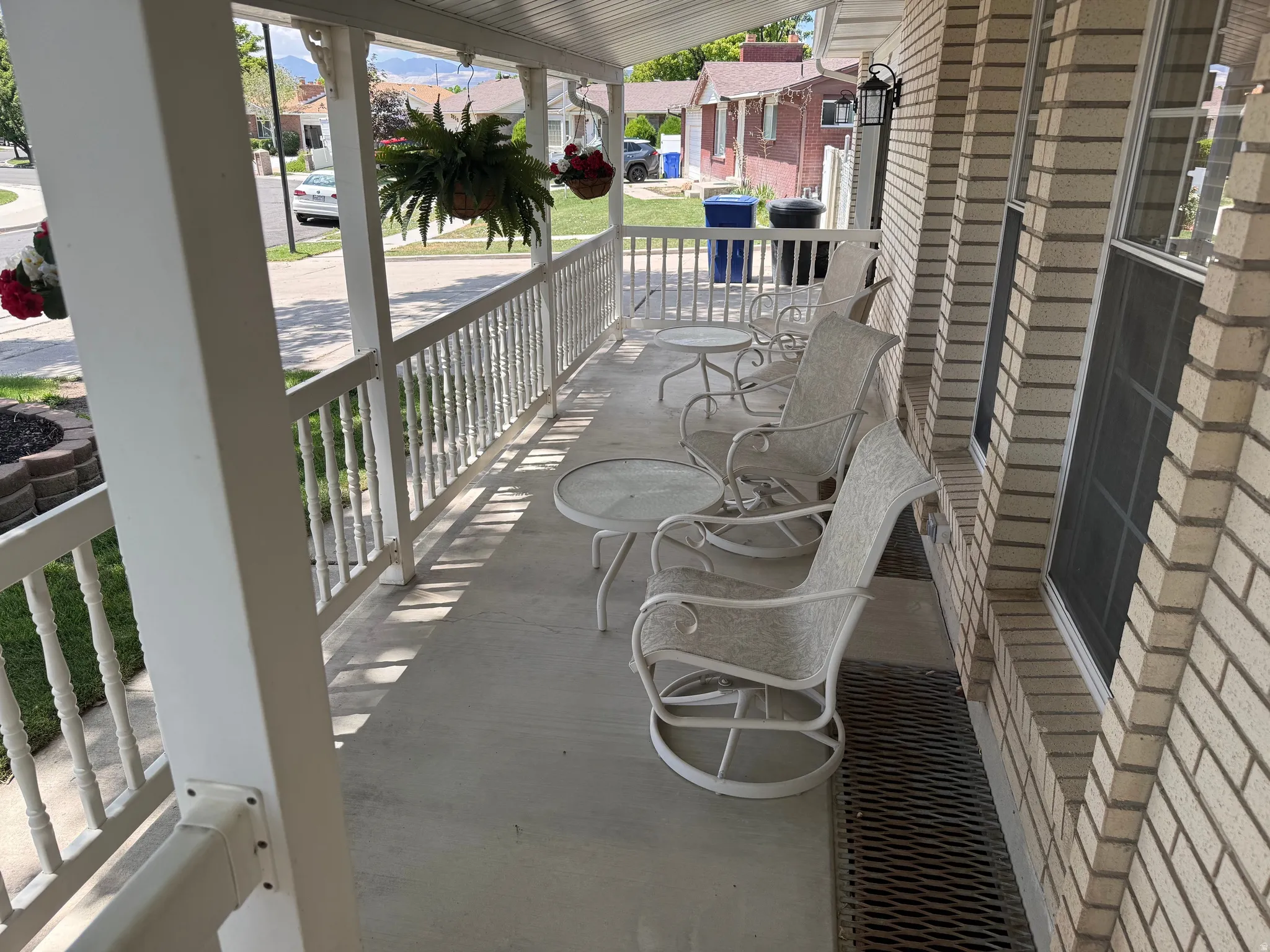 Covered front porch featuring a white spindle railing and a light-colored brick exterior
