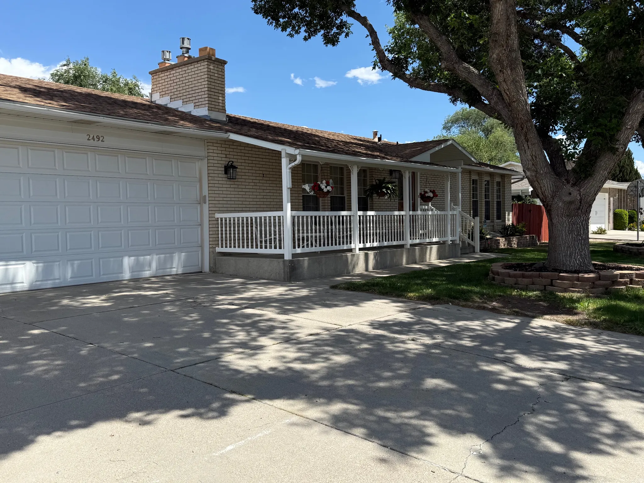 Single-story residence featuring a covered front porch with white railing, light brick facade, and an attached two-car garage