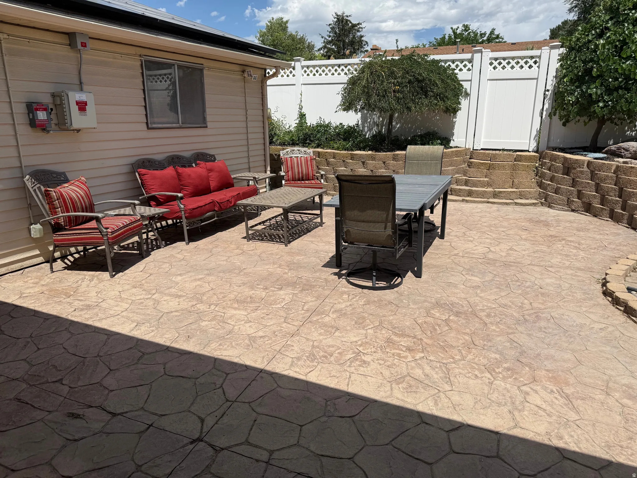 Expansive stamped concrete patio with a tiered retaining wall, offering diverse outdoor living areas