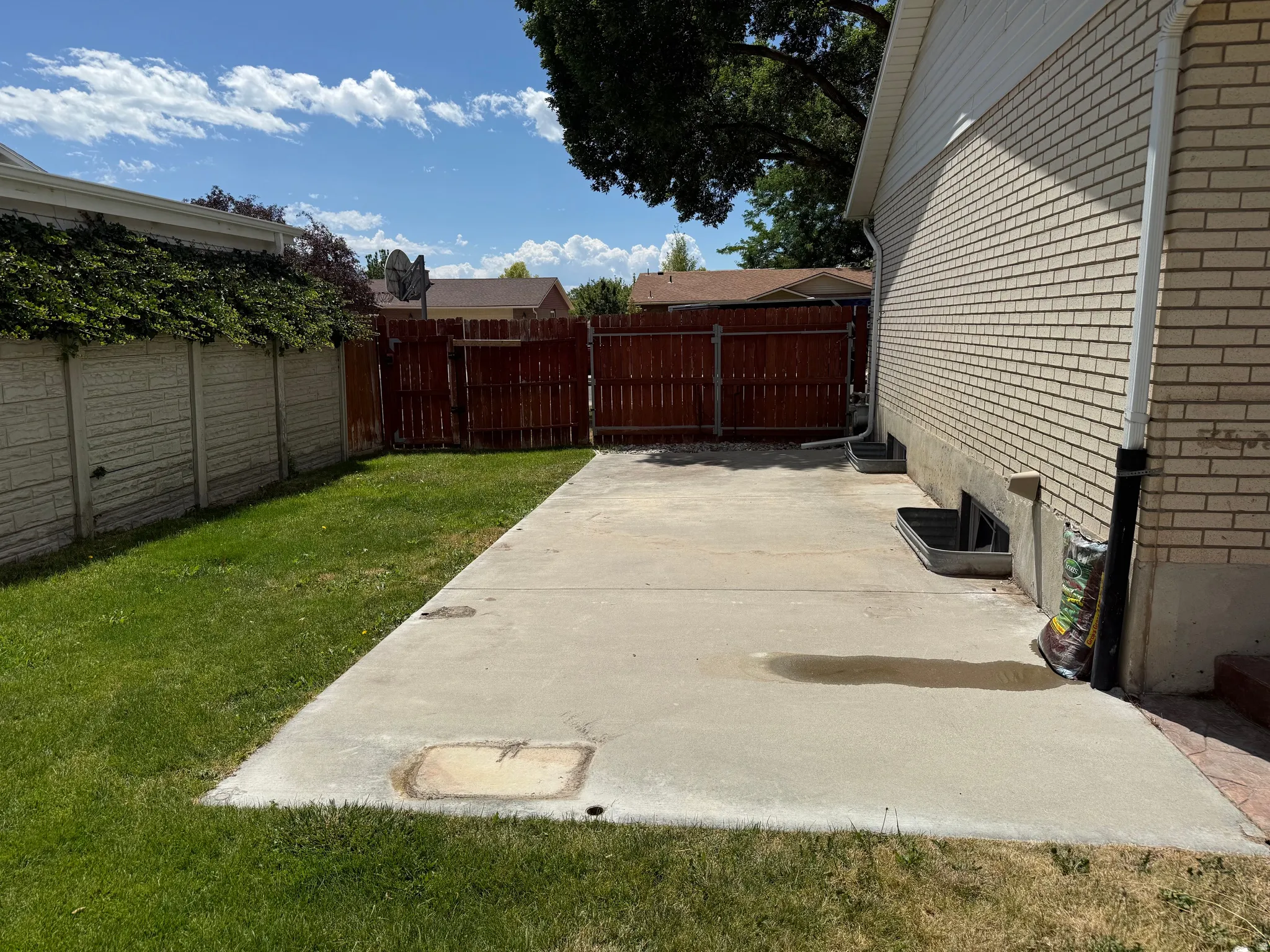 Concrete patio area featuring a brick exterior wall and a wooden privacy fence approximately 10x27