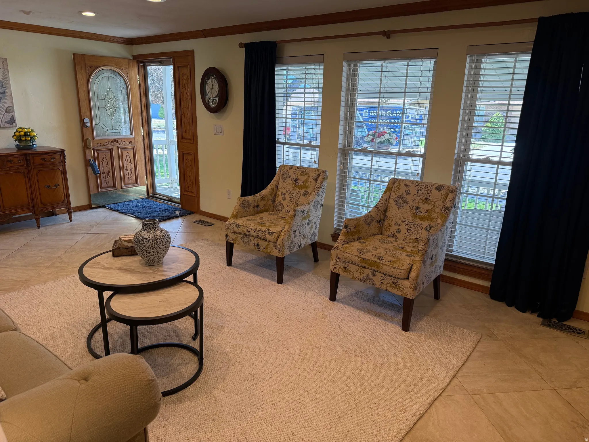 Entryway and living area featuring tile flooring, a decorative wood entry door with leaded glass, multiple windows with blinds, and custom wood trim accents with great natural lighting.
