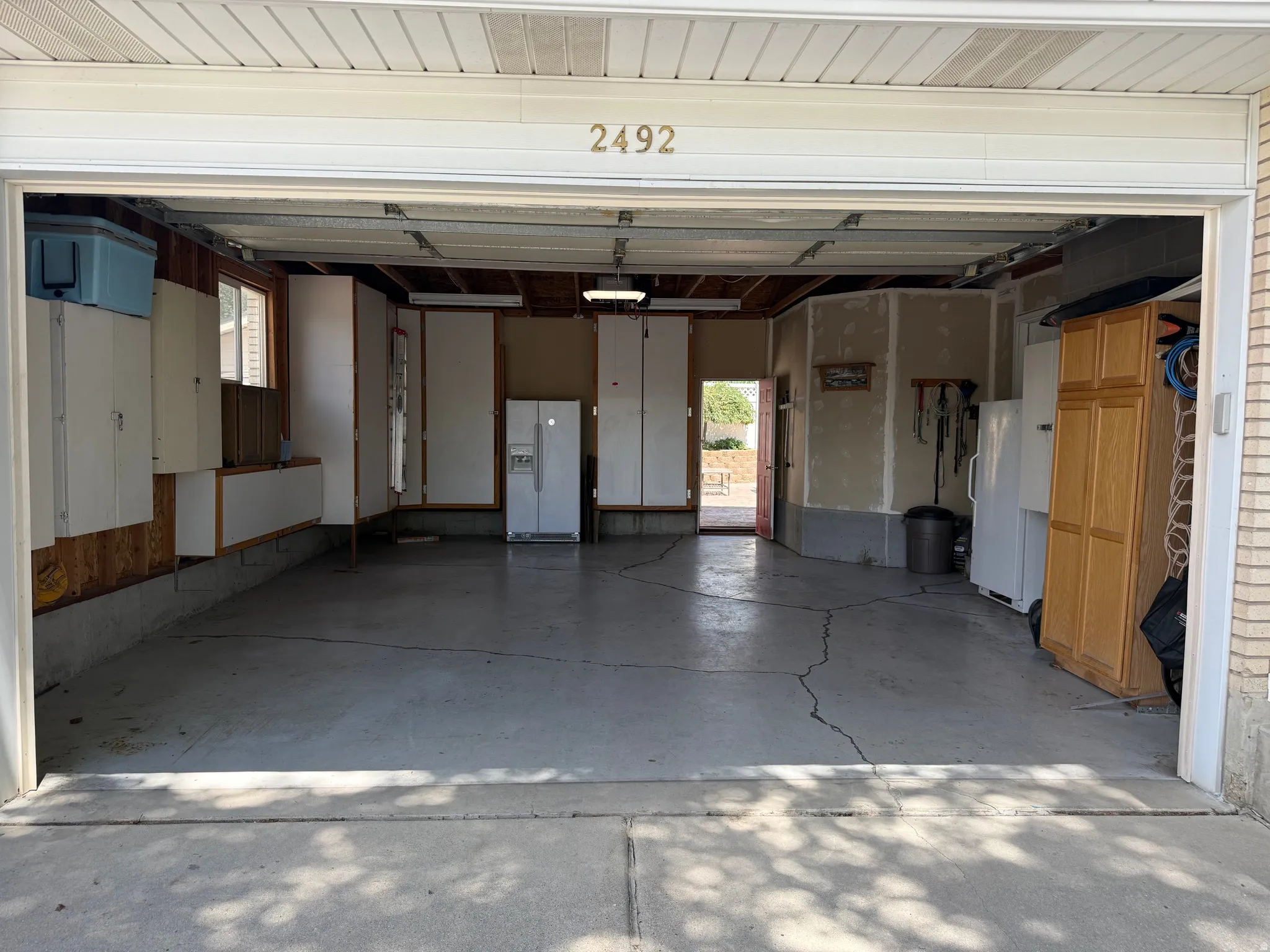 Attached garage with concrete flooring, visible overhead lighting, and built-in cabinetry