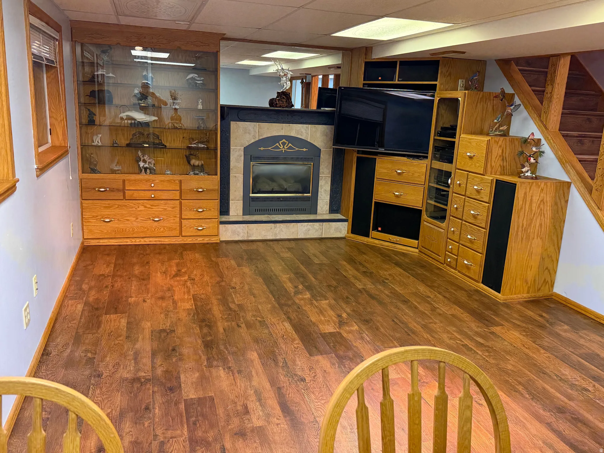 Wood-finish flooring throughout, featuring a built-in entertainment center with integrated cabinetry and a tiled fireplace surround