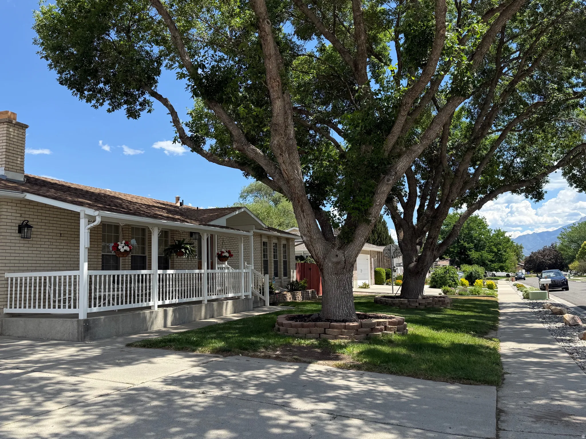 2 Mature trees. Mountain view. Exterior featuring a light brick facade, a covered front porch with white railing, a shingle roof, and a prominent brick chimney