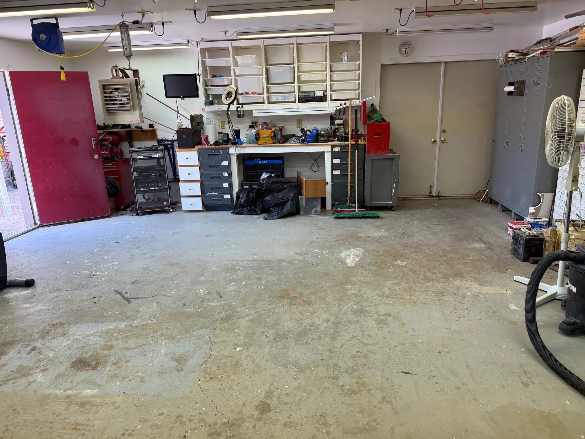 Concrete floor workshop featuring built-in shelving, workbench area, and double-door entry