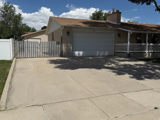 Large RV parking behind the gate. Front exterior featuring a two-car garage, concrete driveway, and covered porch with white railings