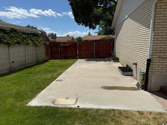 Concrete patio area featuring a brick exterior wall and a wooden privacy fence approximately 10x27