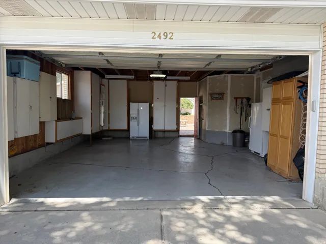 Attached garage with concrete flooring, visible overhead lighting, and built-in cabinetry