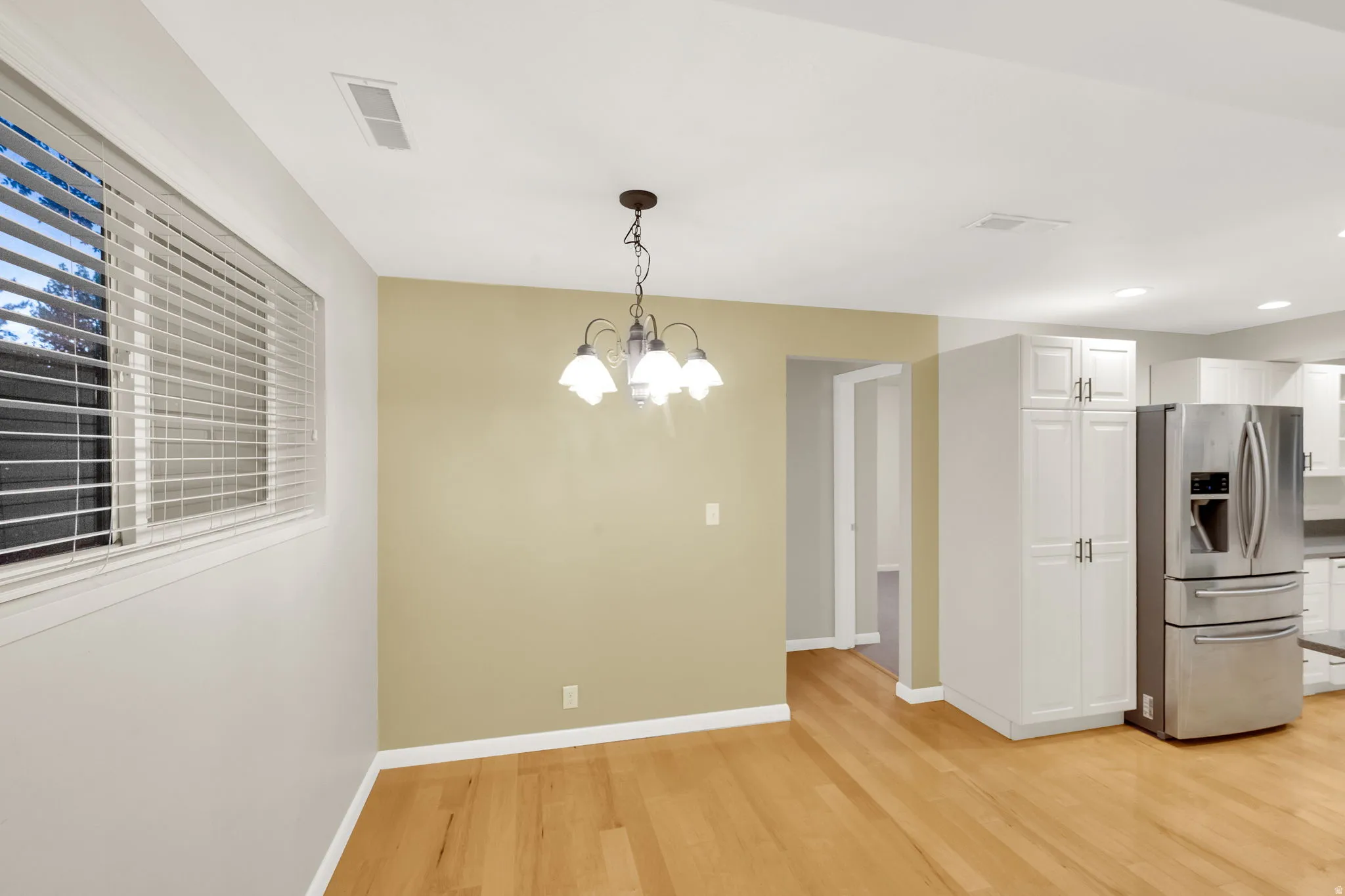 Hardwood-style flooring throughout this dining area, featuring a decorative chandelier
