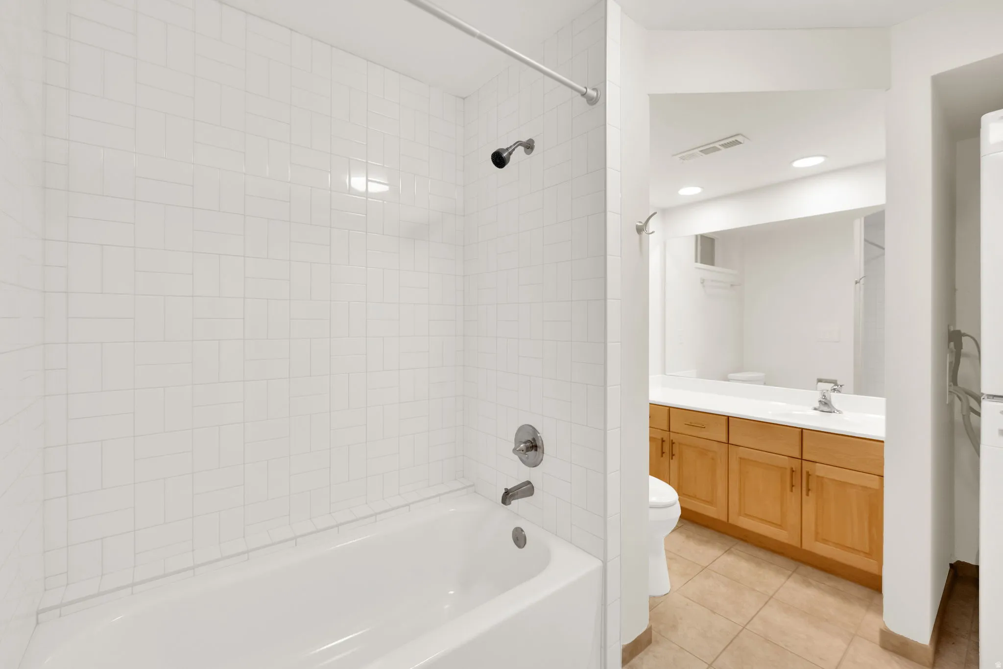 Bathroom featuring a white subway tile shower surround, a white bathtub, and brushed nickel shower fixtures