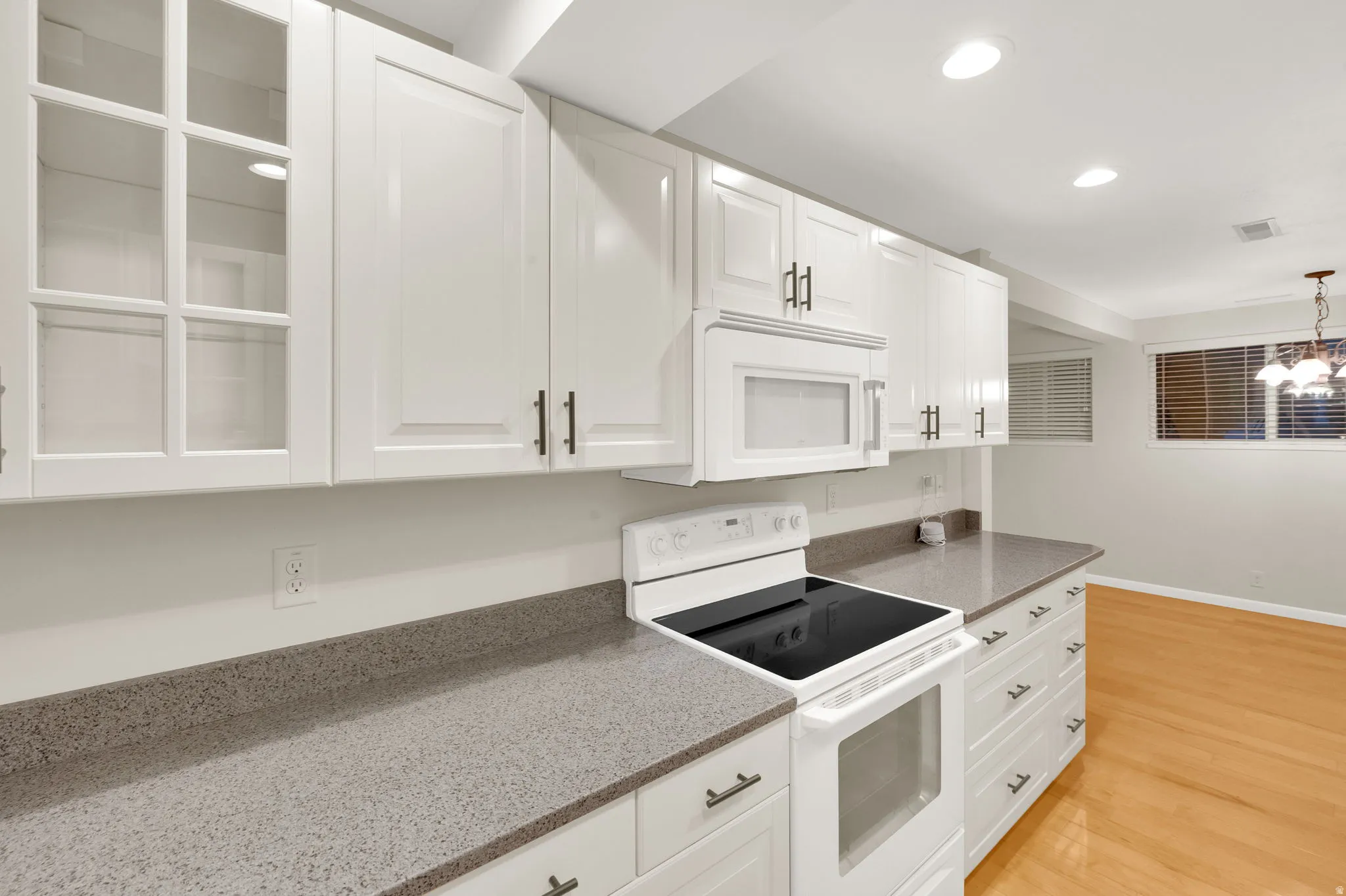 Contemporary kitchen featuring white cabinetry, a built-in microwave, a smooth-top electric range, and speckled countertops